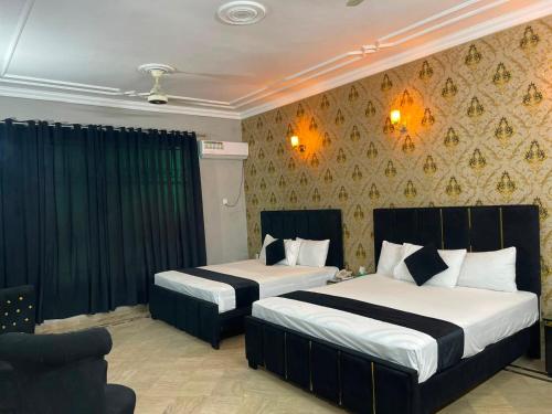 a hotel room with two beds and a couch at Oasis Family Hotel in Lahore