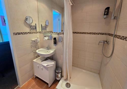 a bathroom with a sink and a shower and a toilet at Hotel AVIVA by APOLONIA in Karlsruhe