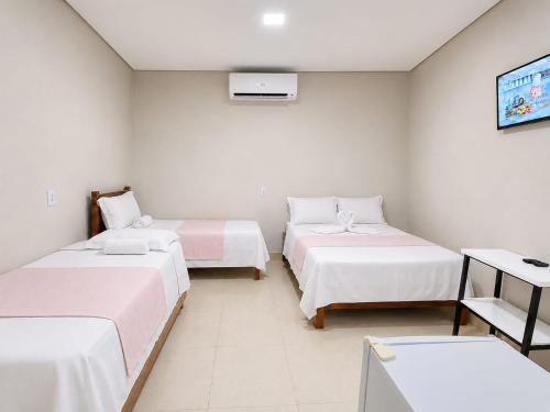 a room with three beds and a tv at Pousada Auroranascerdosol in Manhã