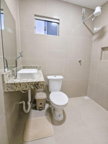 a bathroom with a white toilet and a sink at Pousada Auroranascerdosol in Manhã