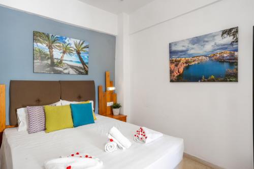a bedroom with a white bed with colorful pillows at Malia Boutique Studios in Malia