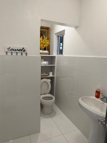 a white bathroom with a toilet and a sink at Your Blooming Getaway in Nassau