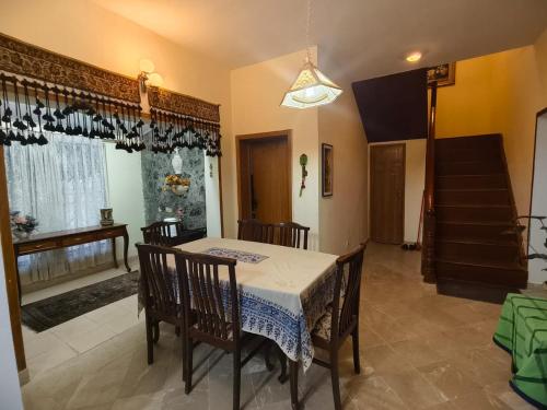 a dining room with a table and chairs and a staircase at Naqvi House in Murree