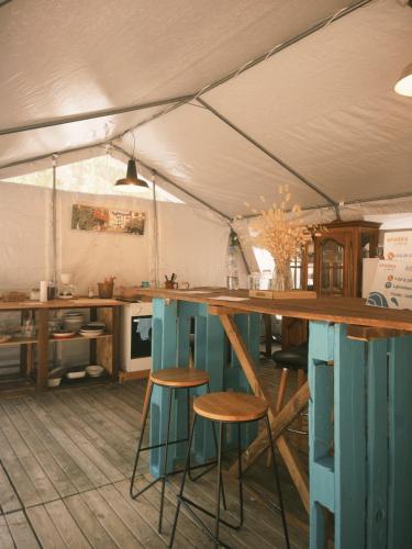 a kitchen with a table and stools in a tent at Auberge Aparra Surfcamp Ondres in Ondres