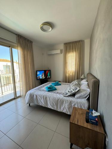 a bedroom with a bed and a table and a tv at Paez Villa - Private Pool - 3BR - Walk to Beach - Pernera Protaras in Protaras