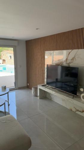 a living room with a large television on a wall at Azure Pool Villa in Marseille