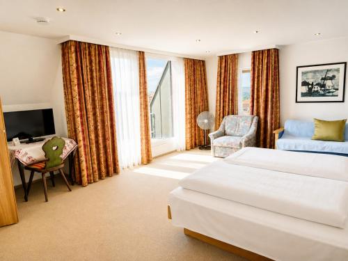 a bedroom with a bed and a desk and a chair at Hotel Tilman Riemenschneider by ANS in Rothenburg ob der Tauber