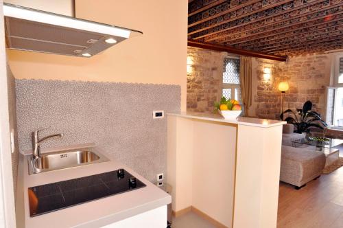 a kitchen with a sink and a living room at Grisogono Palace Heritage Residence in Split