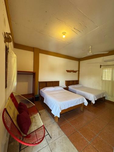 a room with two beds and a chair in it at Casa Santa Elena in Brisas de Zicatela