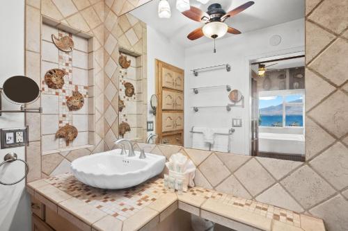 a bathroom with a sink and a large mirror at Menehune Shores 606 - Direct Ocean Front, Split AC in Kihei