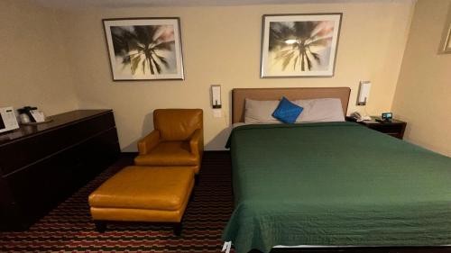 a hotel room with a bed and a chair at Chesaning INN & Suites in Chesaning
