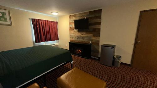 a hotel room with a bed and a fireplace at Chesaning INN & Suites in Chesaning