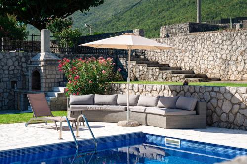 a patio with a couch and an umbrella next to a pool at Luna Pool Apartment in Danilovgrad