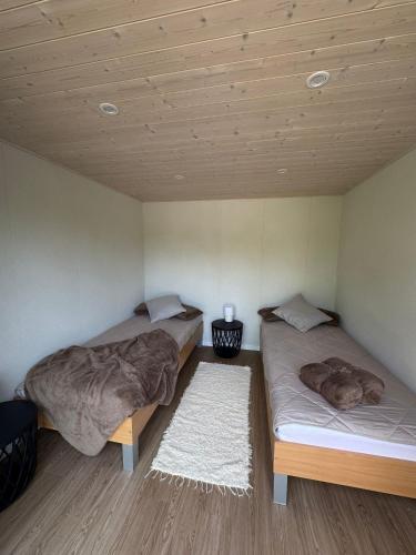 two beds in a room with wooden ceilings at Nowa Pasłęka - Domki Passarge in Braniewo