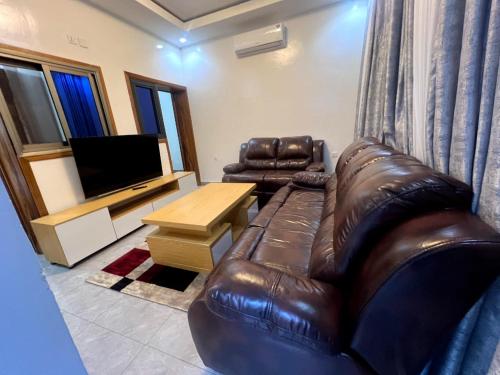 a living room with a leather couch and a television at Comfort Deluxe Apart in Kigali