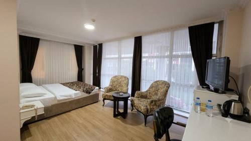 a bedroom with a bed and two chairs and a tv at Ottoman Hotel Sakarya in Sakarya