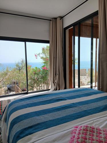 a bedroom with a bed with a view of the ocean at Dar Isma : Une maison sur océan in Wassane
