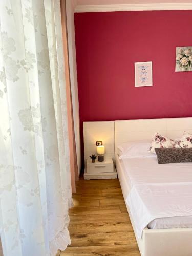 a bedroom with a white bed and a red wall at Casa Trio in Tirana