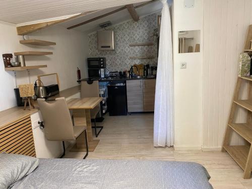 a room with a bed and a kitchen with a table at Mini gîte Hérisson - 18m2 in Songeson