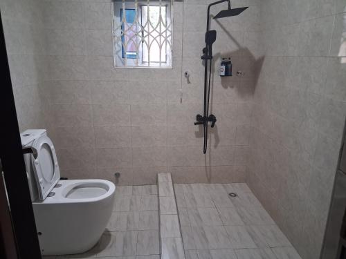 a bathroom with a toilet and a shower with a window at Snl Mountain View Hotel in Oko Sombo