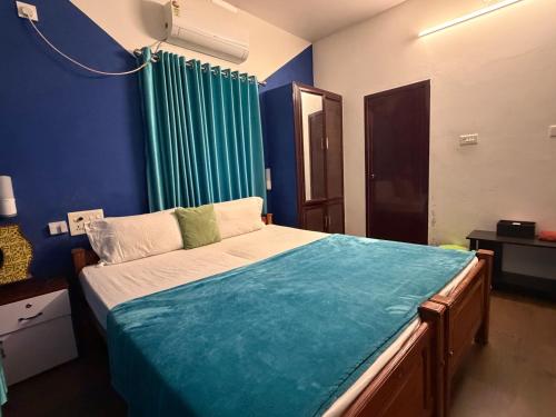 a bedroom with a large bed with a blue wall at Mud apples stay in Varkala