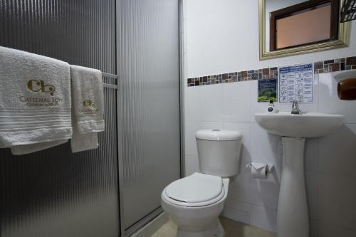a white bathroom with a toilet and a sink at Hotel Catedral Boutique Loft in Pasto