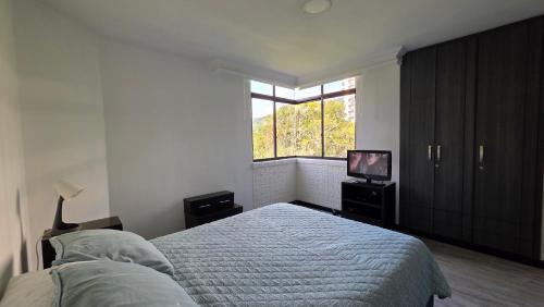 a bedroom with a bed and a window and a television at Pent House La Castellana in Armenia