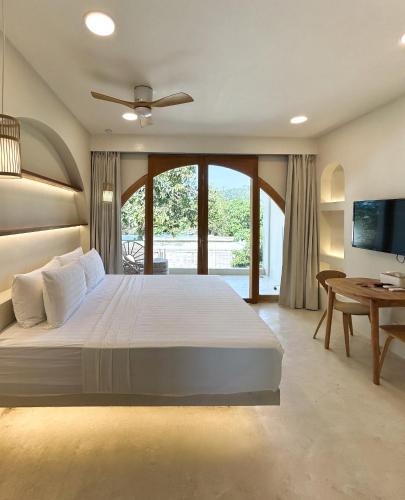 a bedroom with a large white bed and a table at Namal Resort - Free scooter and Gym access in El Nido