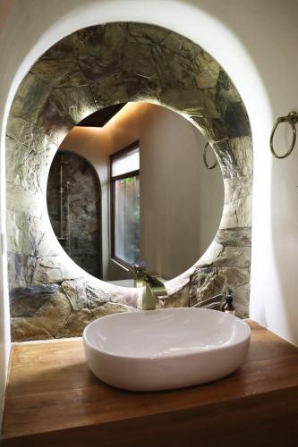 a bathroom with a sink and a round mirror at Namal Resort - Free scooter and Gym access in El Nido