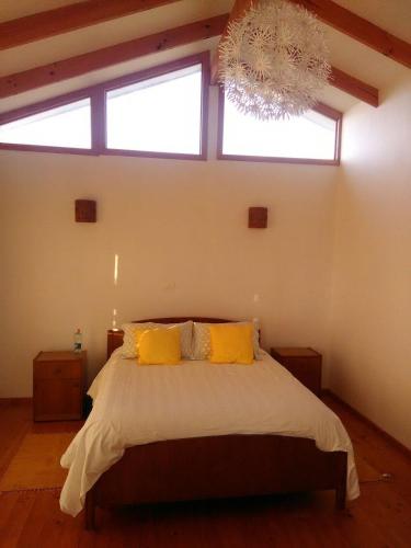 a bedroom with a bed with yellow pillows and a chandelier at Cabanas Las Hualas in Punta de Choros