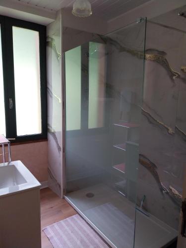 a glass shower in a bathroom with a sink at Location Fermette in Goulles