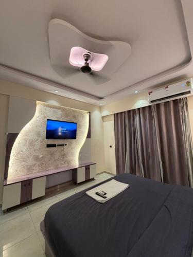 a bedroom with a bed and a flat screen tv at Aureva stays Omaxe Hazratganj in Nalmatha