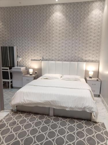 a bedroom with a large white bed and two tables at شاليه ريف المملكة in Hail