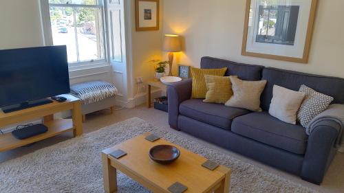 a living room with a blue couch and a tv at Turret View - spacious central location in Peebles