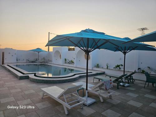 a swimming pool with chairs and umbrellas and a pool at Appartement Touta écologique familial in Ḩawmat al Badawīyīn