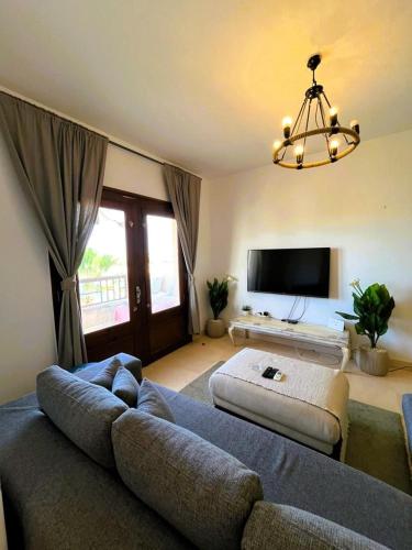 a living room with a couch and a tv at Sabina 2BD with pool and lagoon view in Hurghada