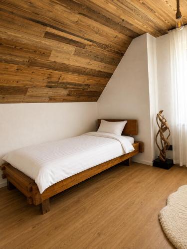 a bed in a room with a wooden ceiling at Topli kutak Golija in Novi Pazar