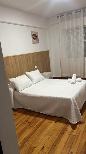 a large white bed in a room with a wooden floor at Hotel Termas Camino Real in Ourense