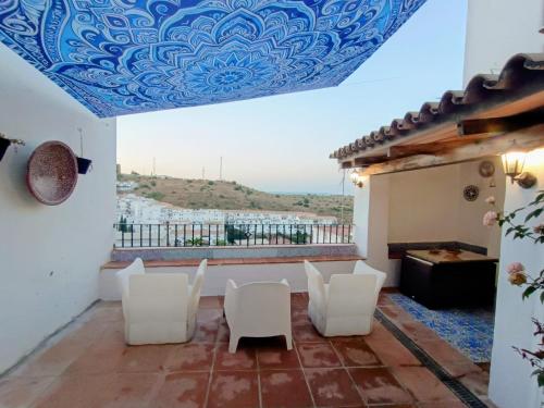 a patio with white chairs and a blue ceiling at Ideal Perros Patio Privado Casa Jaruf in Arcos de la Frontera