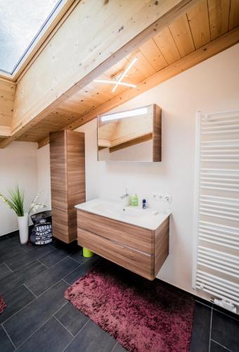 a bathroom with a white sink and a wooden ceiling at Tyrolhaus in Grinzens