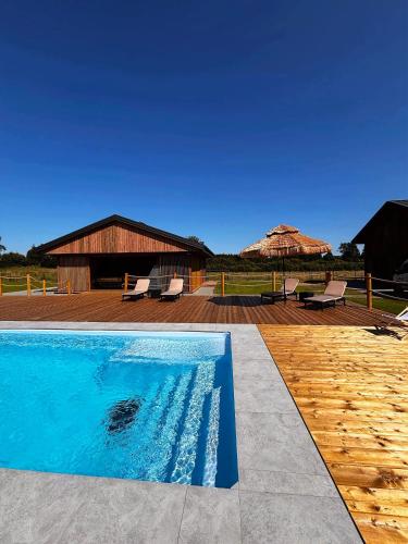 a swimming pool with two umbrellas and a house at Z Nurtem Rzeki Domy z basenem Podlasie in Korycin