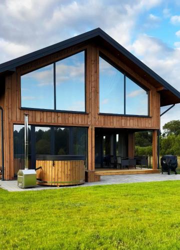 a large wooden house with large windows at Z Nurtem Rzeki Domy z basenem Podlasie in Korycin