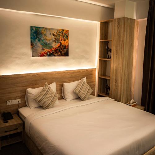 a bedroom with a bed with a painting on the wall at Consal Hotel 康赛尔酒店 in Baghdād