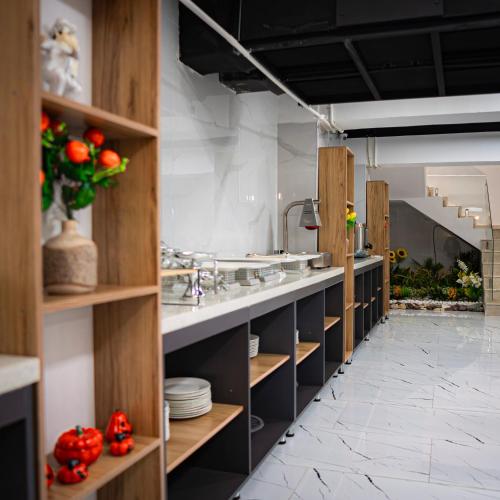 a kitchen with wooden shelves and sinks and red flowers at Consal Hotel 康赛尔酒店 in Baghdād