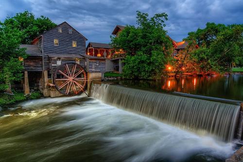 a river with a mill and a water wheel at By The Night in Pigeon Forge
