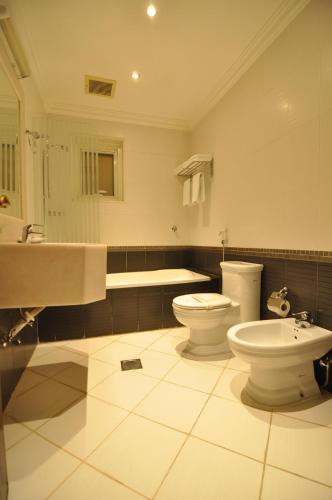 利雅德的住宿－尼落芙阿拉達酒店，浴室设有2个卫生间、水槽和浴缸。