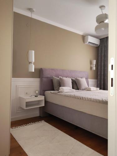 a bedroom with a bed with a purple headboard at Velvet Point apartmant in Kragujevac