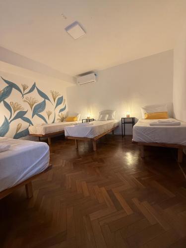 a room with four beds in it with a wooden floor at Clivias Hostel in Salta