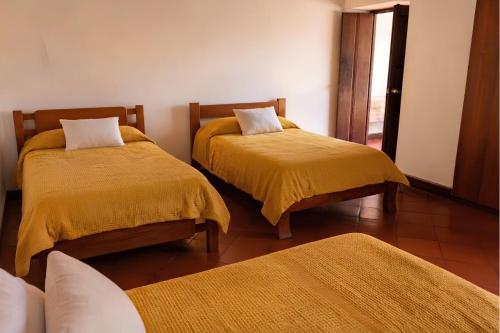 a bedroom with two beds with yellow blankets and a window at La Casona Santa Fe in Santa Fe de Antioquia