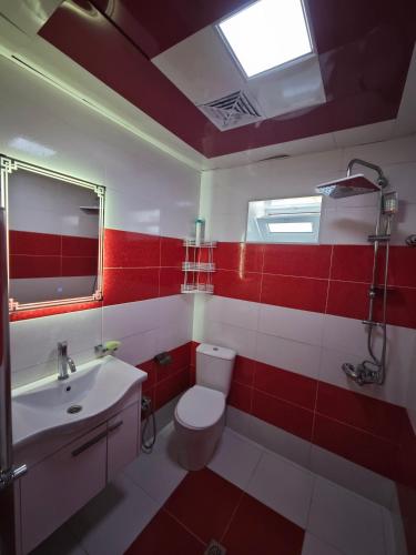 a red and white bathroom with a toilet and a sink at Qebele Romi Family House in Vǝndam